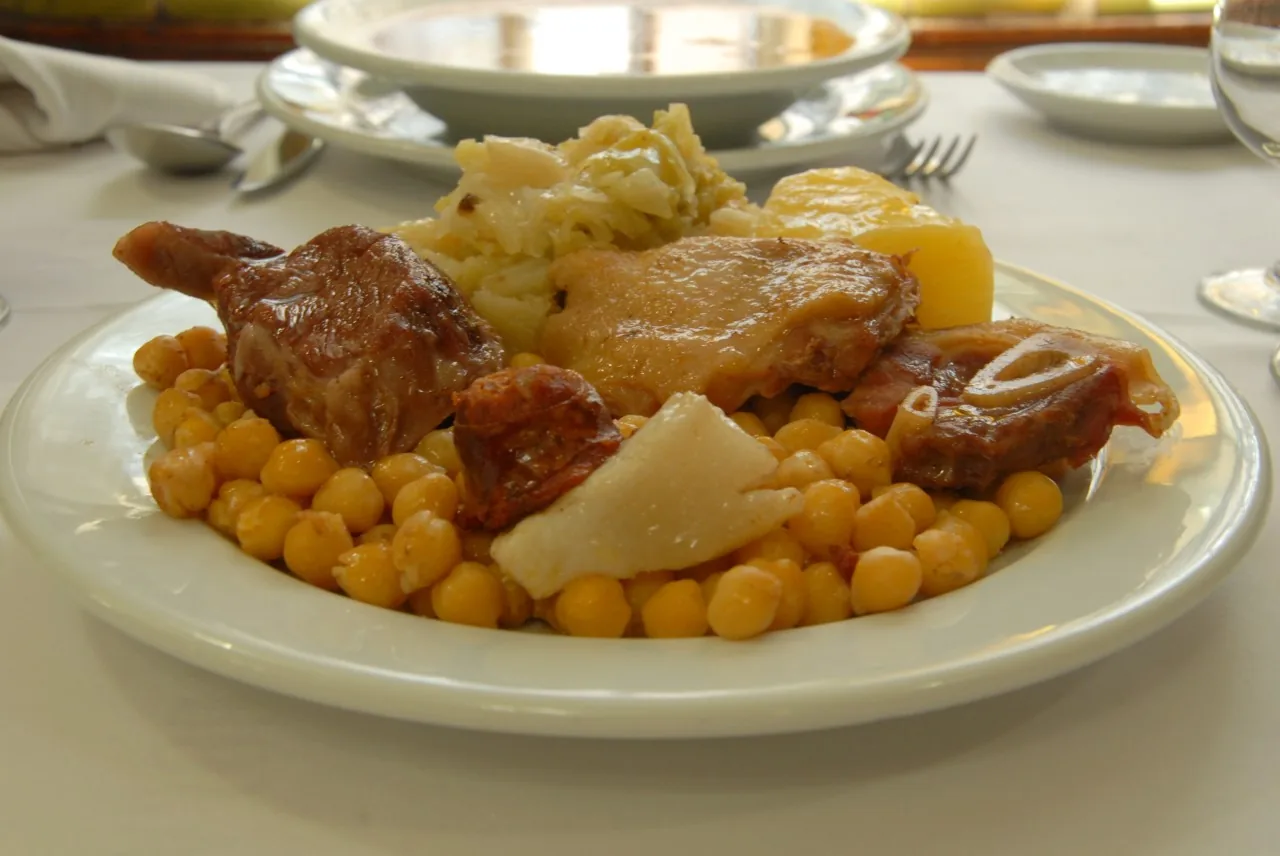A plate of cocido madrileno with meat, chickpeas, and vegetables