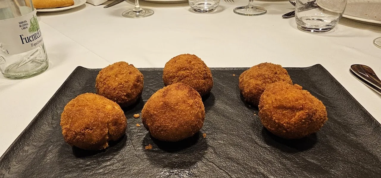 Five golden croquettes on a black slate plate