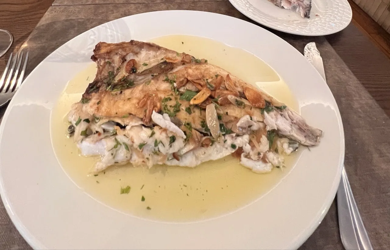 A whole grilled fish fillet in a lemon butter sauce