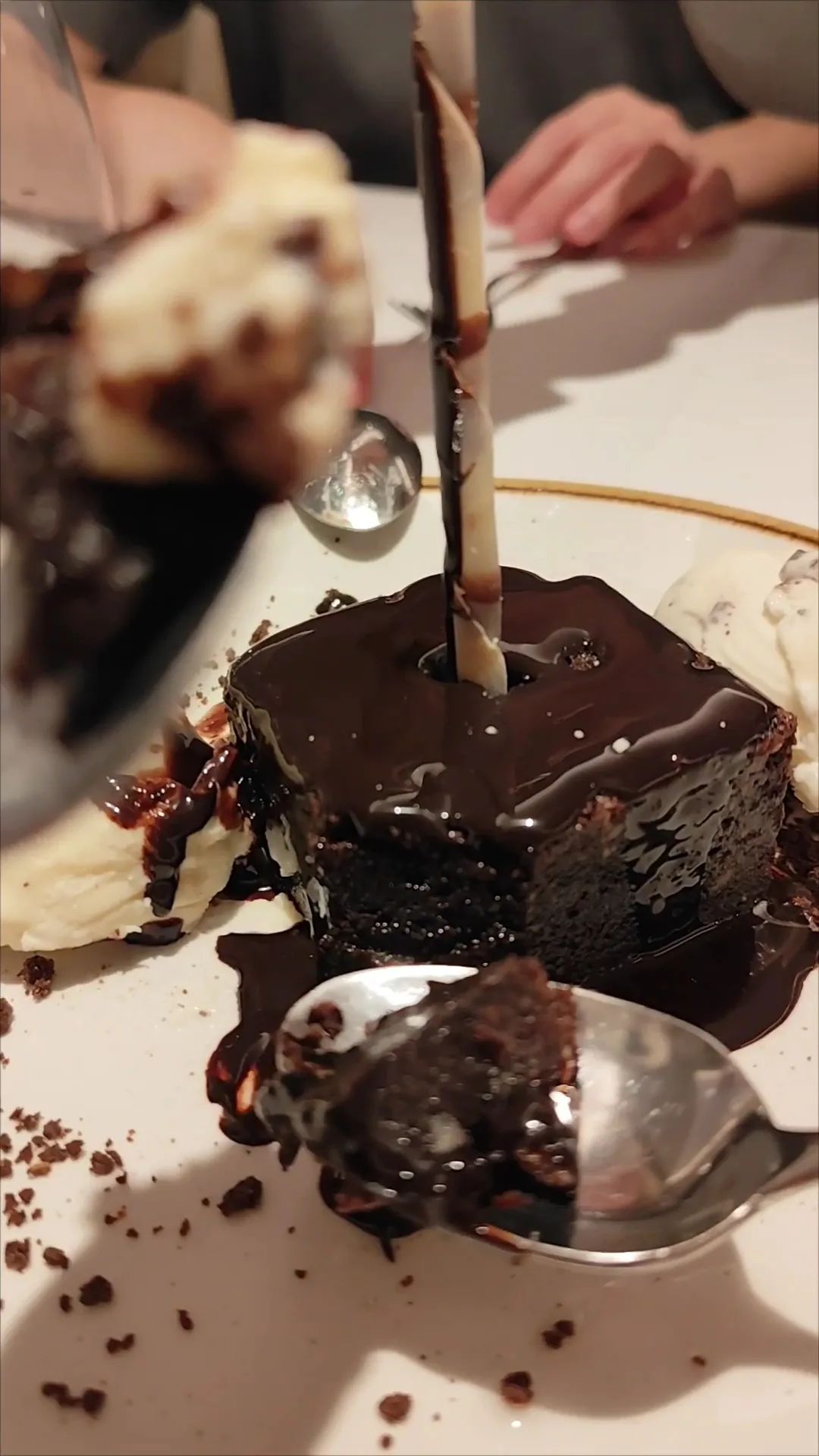 A chocolate dessert drizzled with sauce, garnished with a wafer