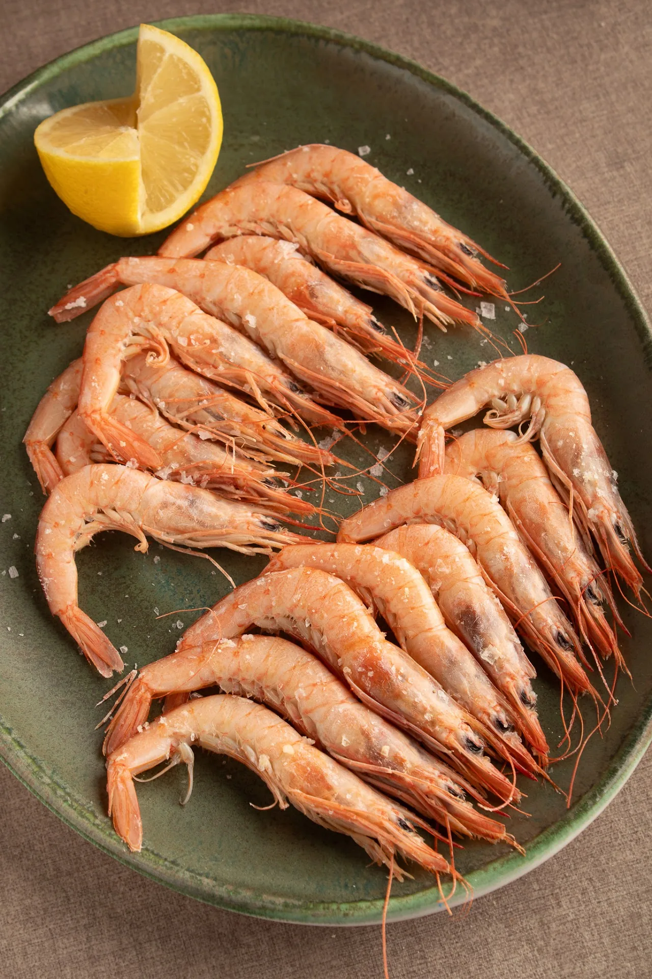 A plate of grilled shrimp with a lemon wedge