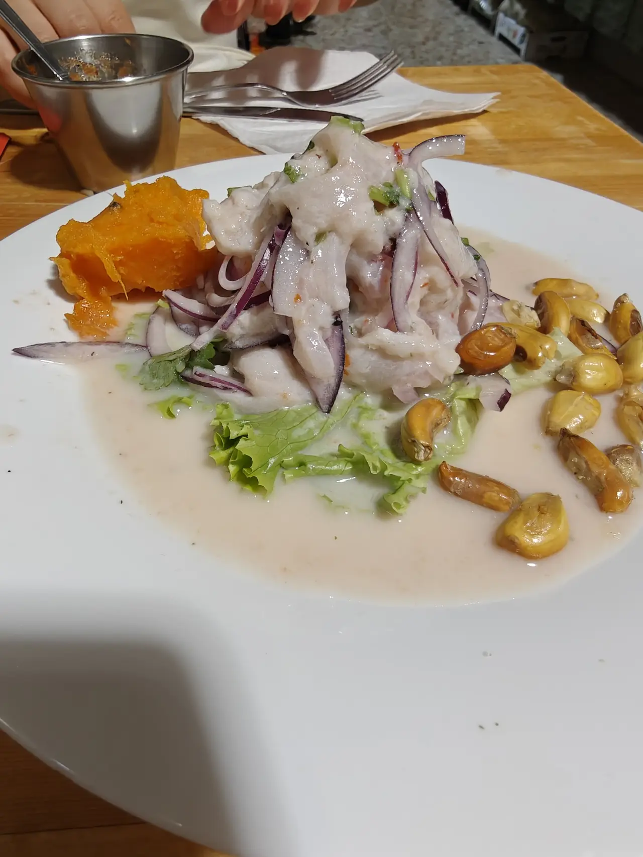 Peruvian ceviche with red onion and toasted corn kernels, served with a piece of sweet potato