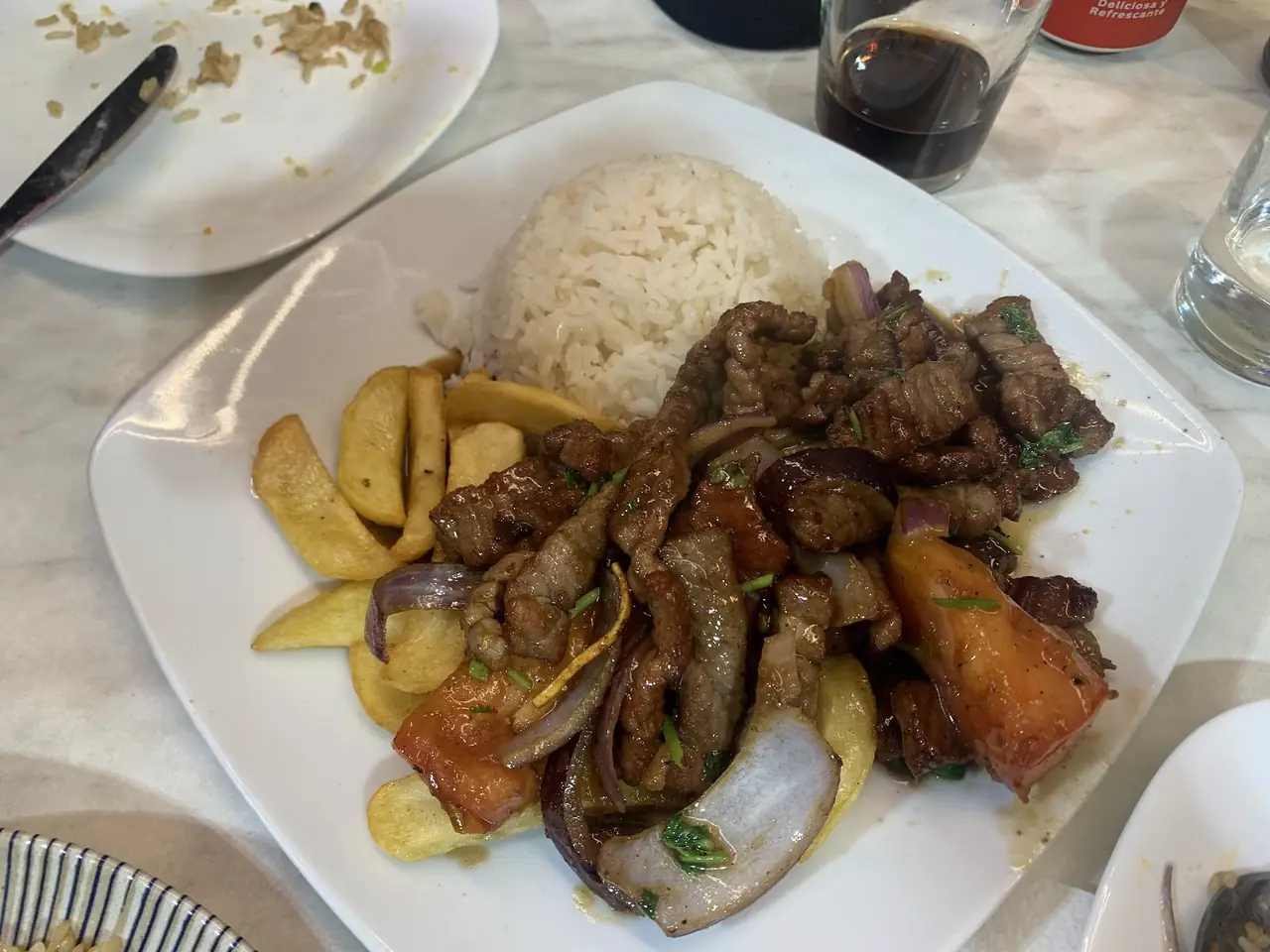 Lomo saltado, stir-fried beef with onions and tomato, served with white rice and fries