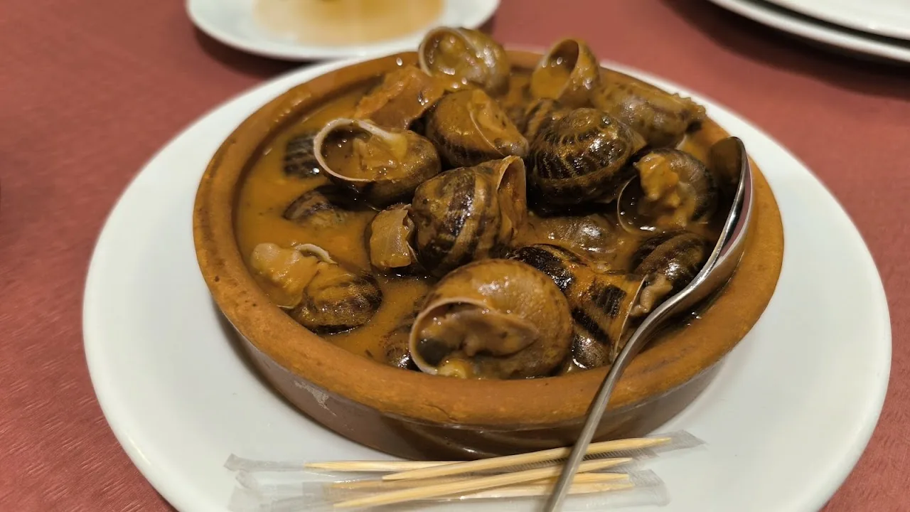 A bowl of cooked snails in broth with toothpicks