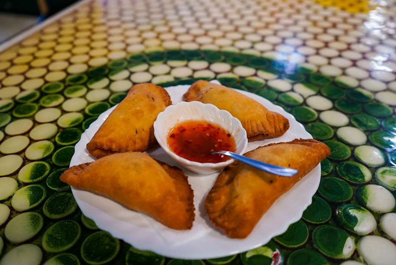 Four fried empanadas served with a red dipping sauce