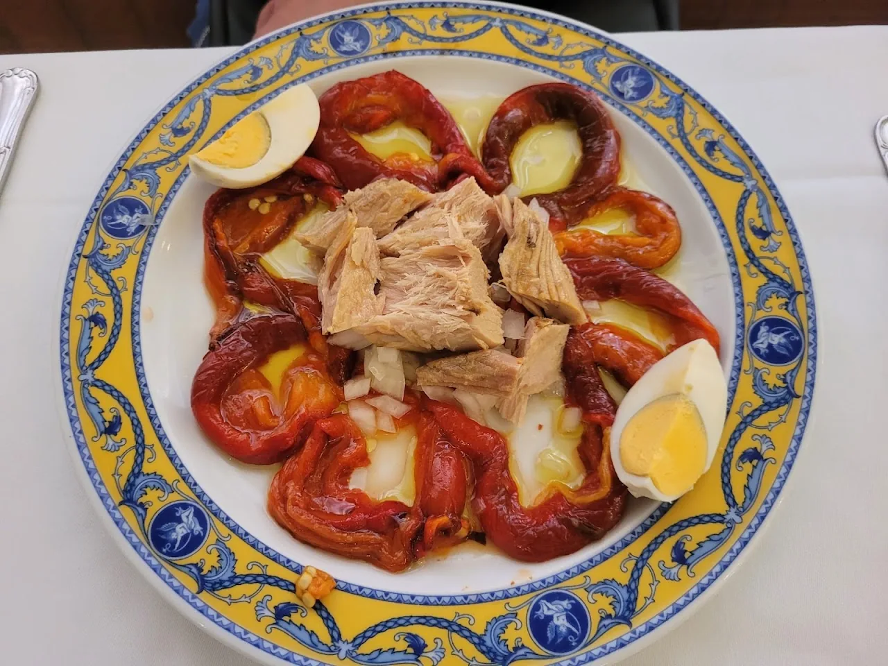 A plate of tomato salad with tuna, egg and red peppers