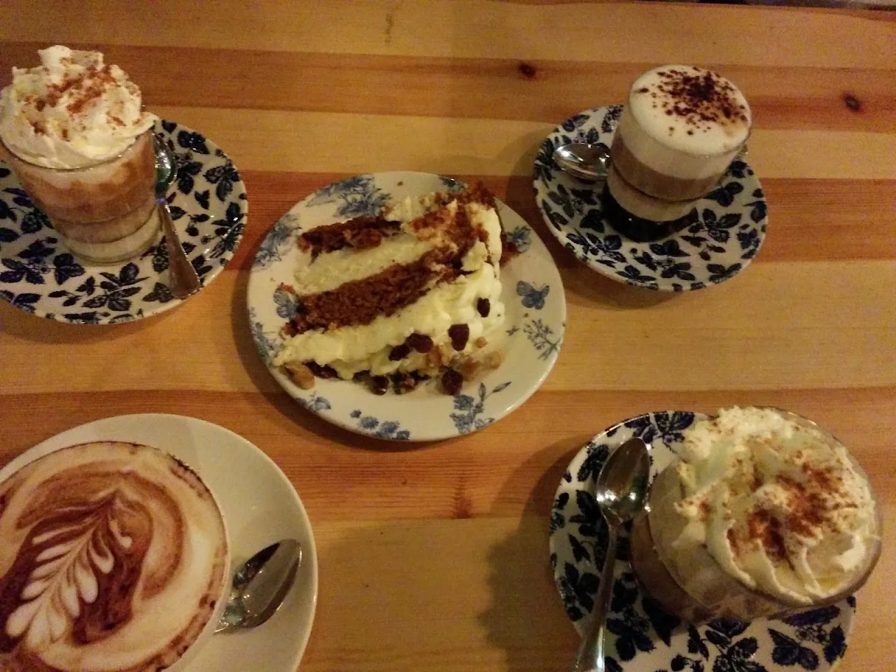 Two cappuccinos and a slice of cake on a wooden table