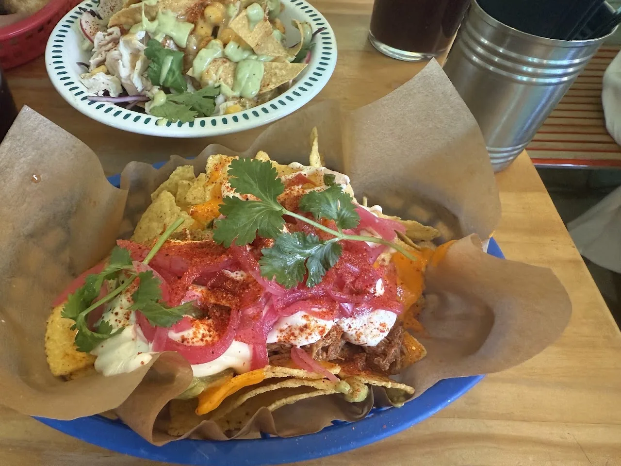 A plate of loaded nachos with pickled onion and greens