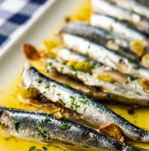 Grilled sardines with herbs in a golden oil