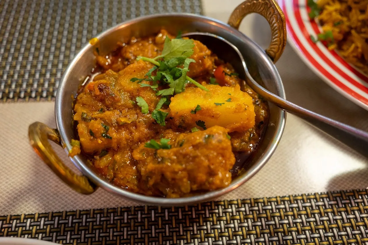 A copper bowl of chicken curry with potatoes