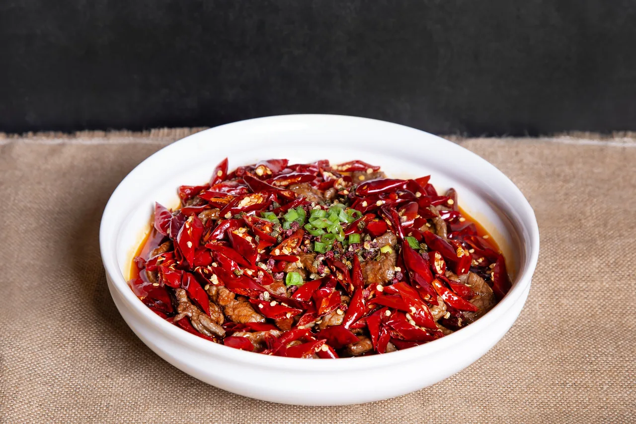 A white bowl of dried red chillies with meat