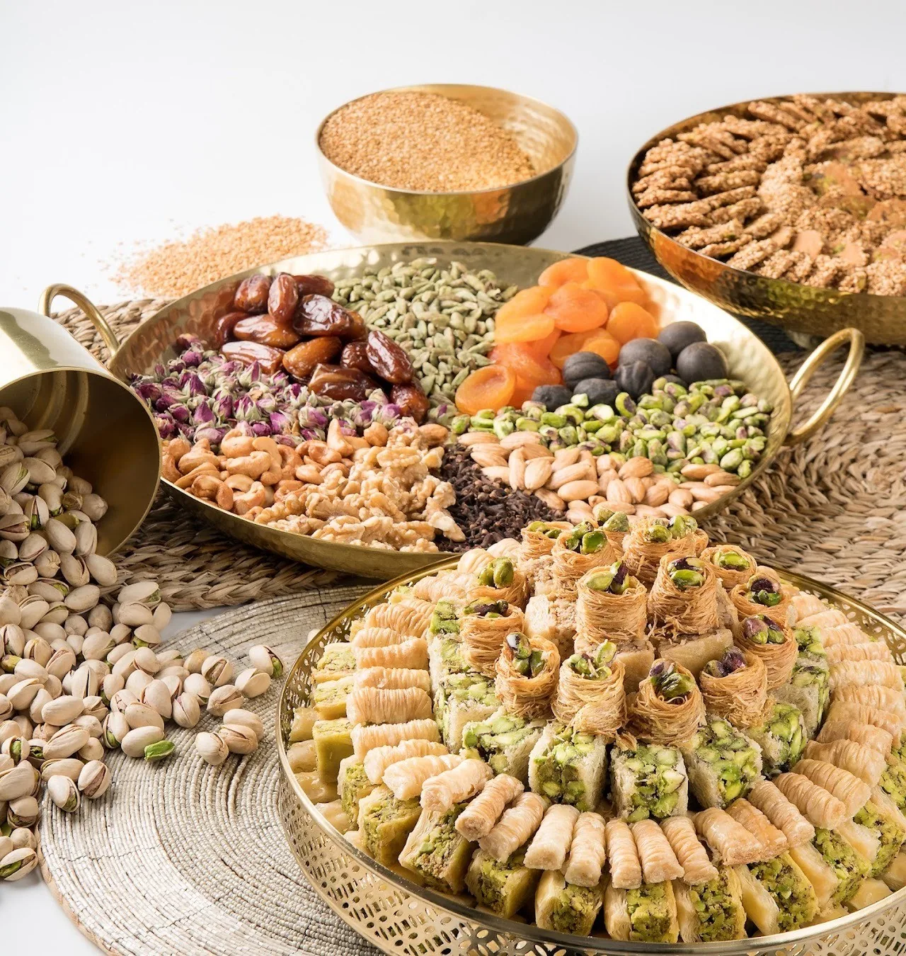 A brass platter of assorted pastries and baklava surrounded by nuts and dried fruit