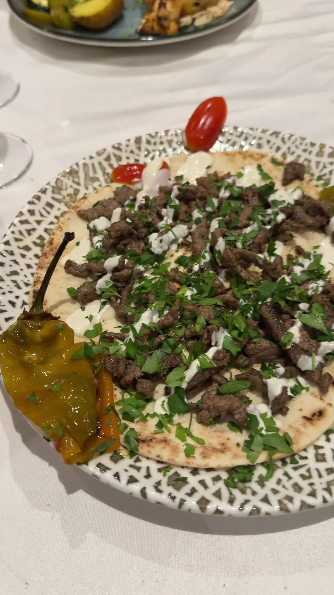 A plate of hummus topped with spiced meat and pine nuts