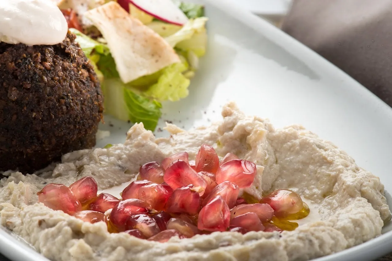 A plate of falafel with hummus and pomegranate seeds