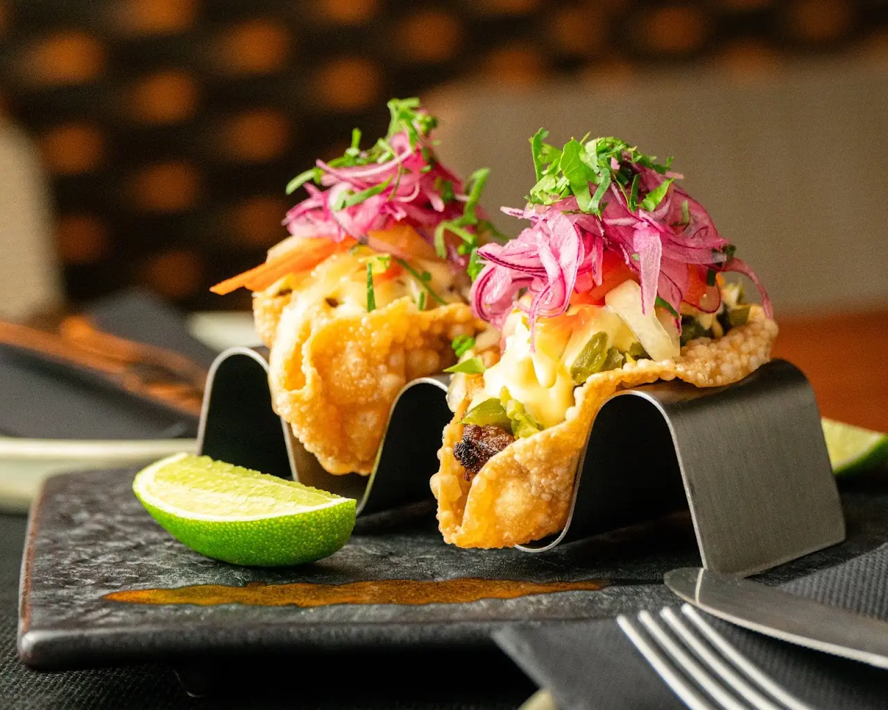 Crispy tostadas topped with pickled pink onion and greens, served with a lime wedge.