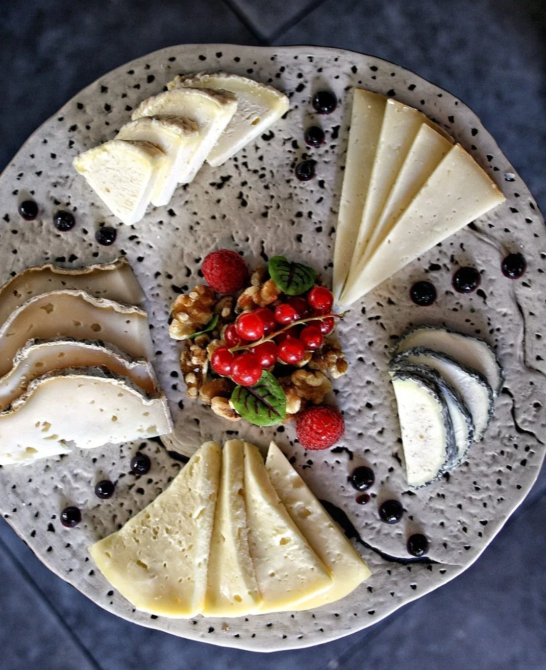 A board of sliced cheeses with berries and nuts
