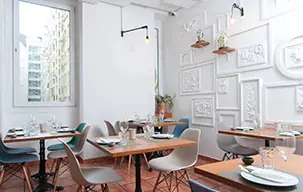Bright dining room with framed wall art, wood tables, and blue and white chairs