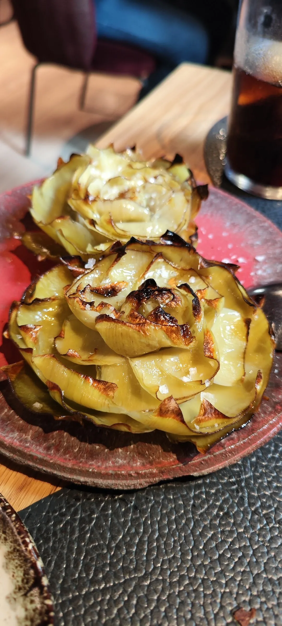 A roasted artichoke topped with shaved cheese on a plate