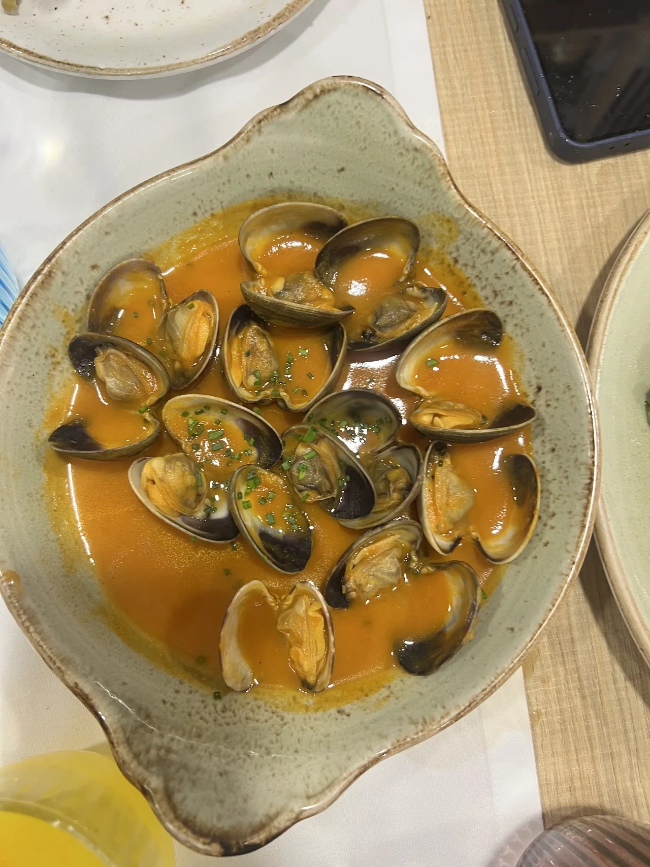 A bowl of mussels in orange broth