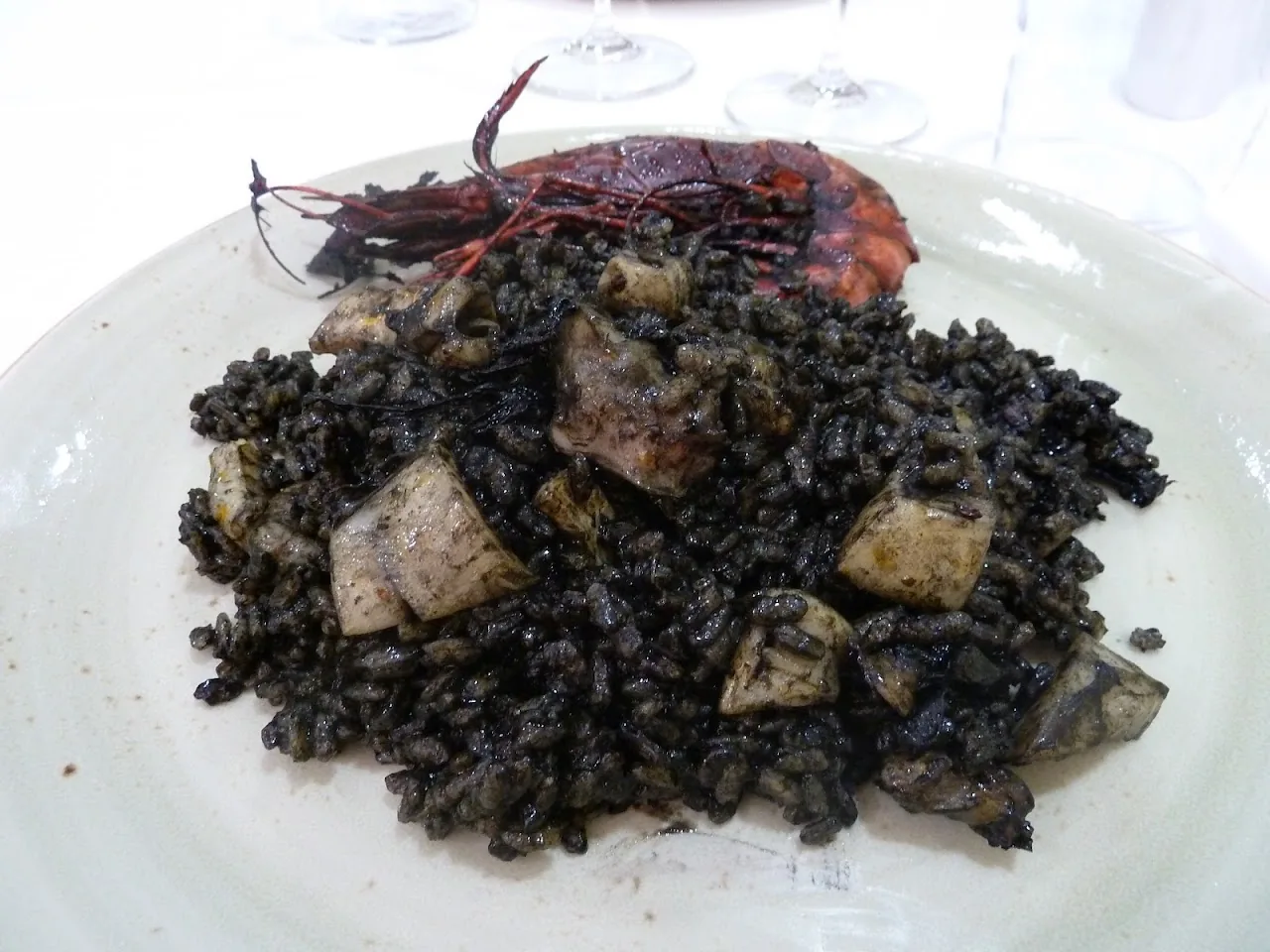 A plate of black rice with seafood and diced ham