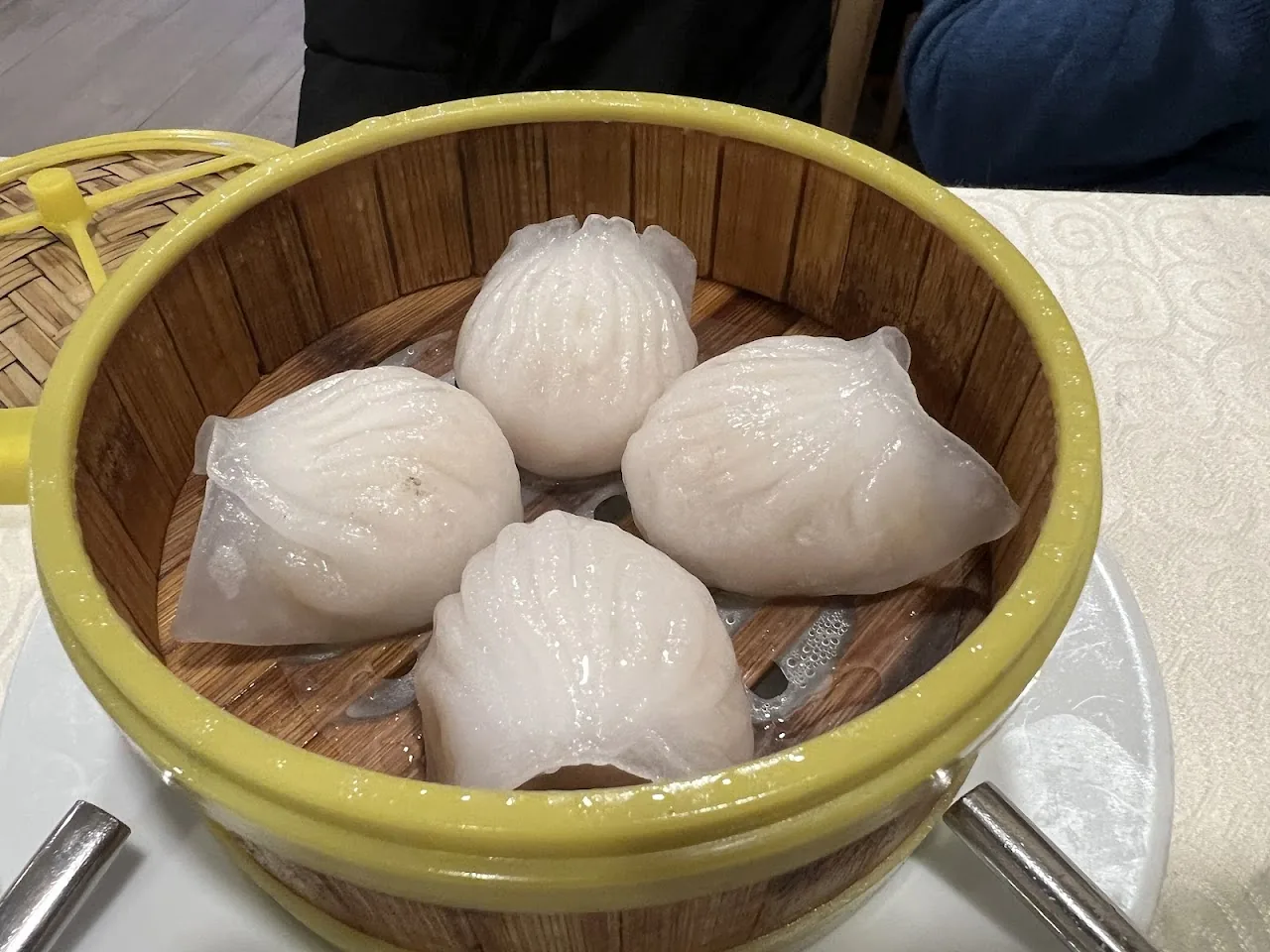 A bamboo steamer basket with four steamed white buns