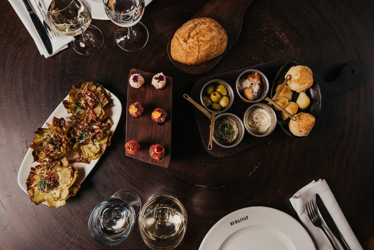An overhead view of several sharing plates and small dishes on a dark wooden table