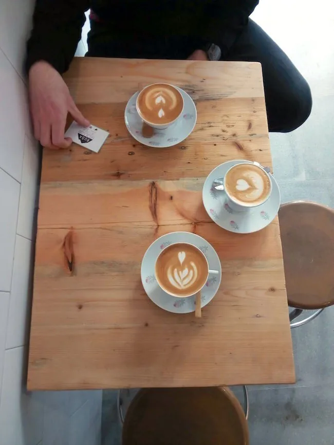 Three cups of coffee with latte art on saucers on a wooden table seen from above