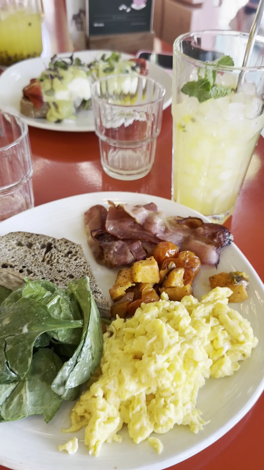 A breakfast plate of scrambled eggs, greens and roasted potatoes