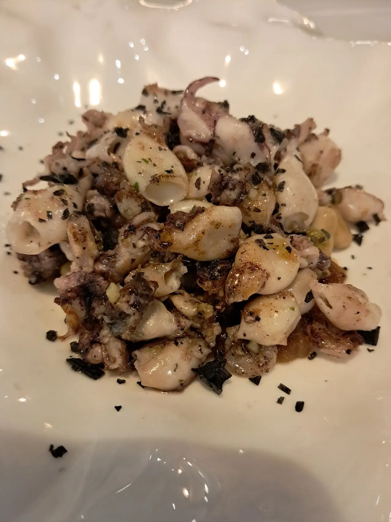 Chopped seafood with a dark seasoning on a white plate