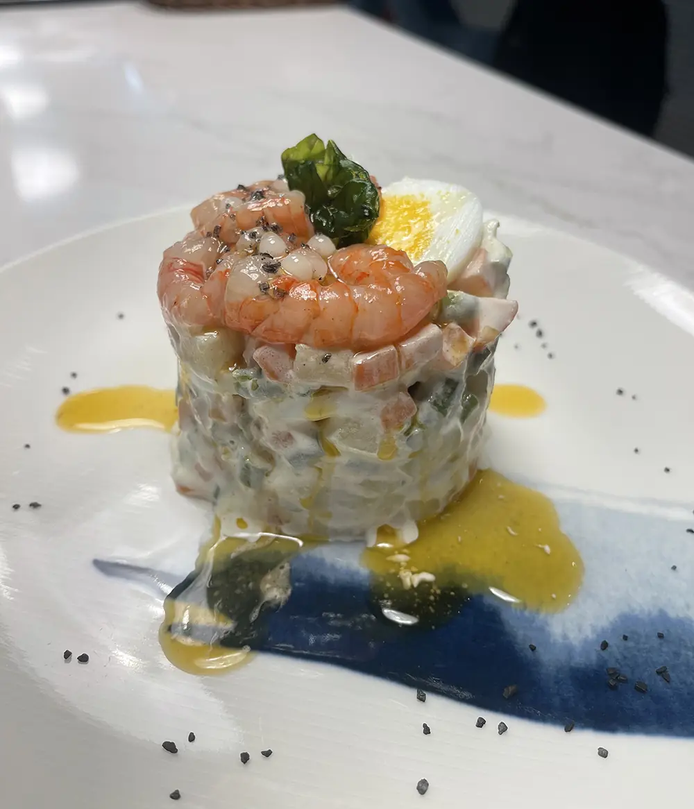 A shrimp and seafood tower topped with a boiled egg wedge