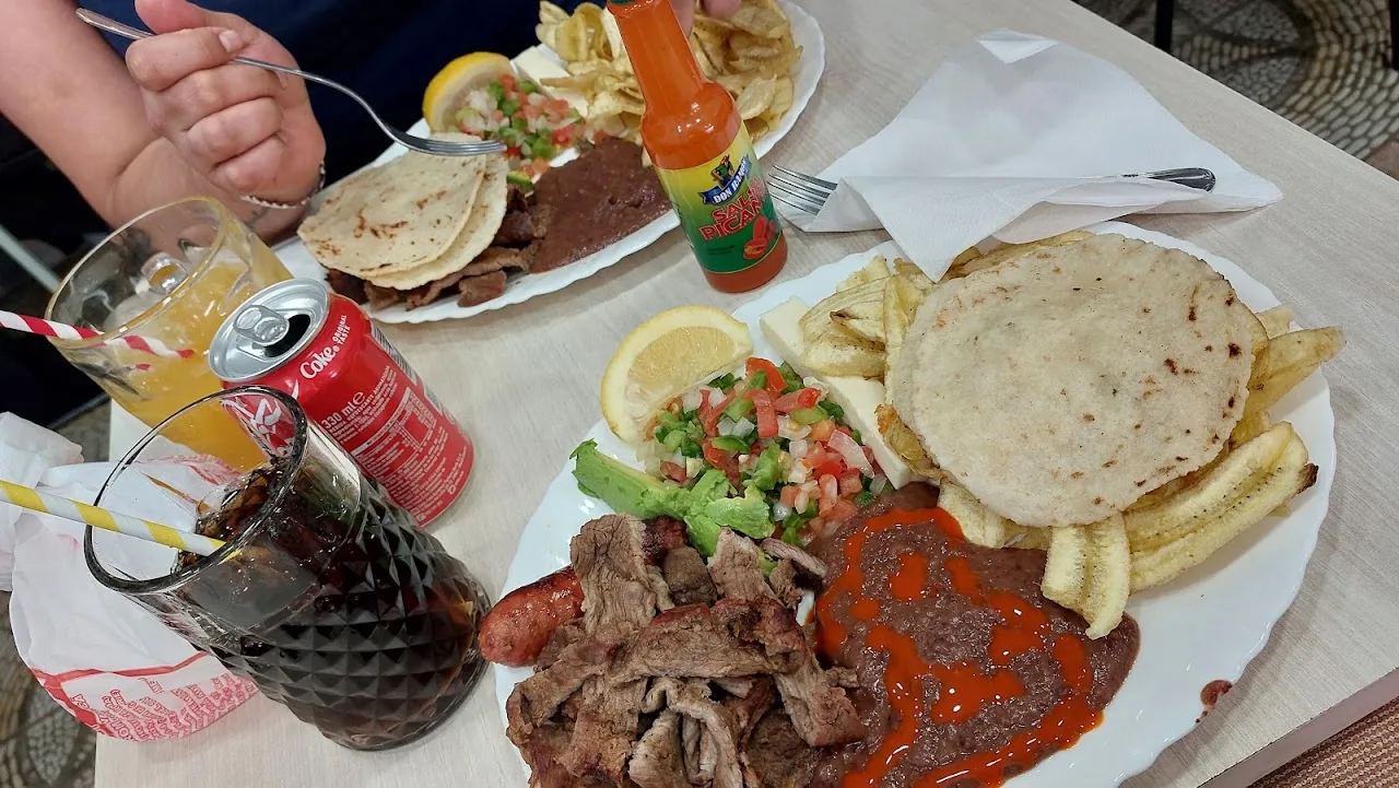 A table spread of tacos and tortillas with hot sauce and salsa