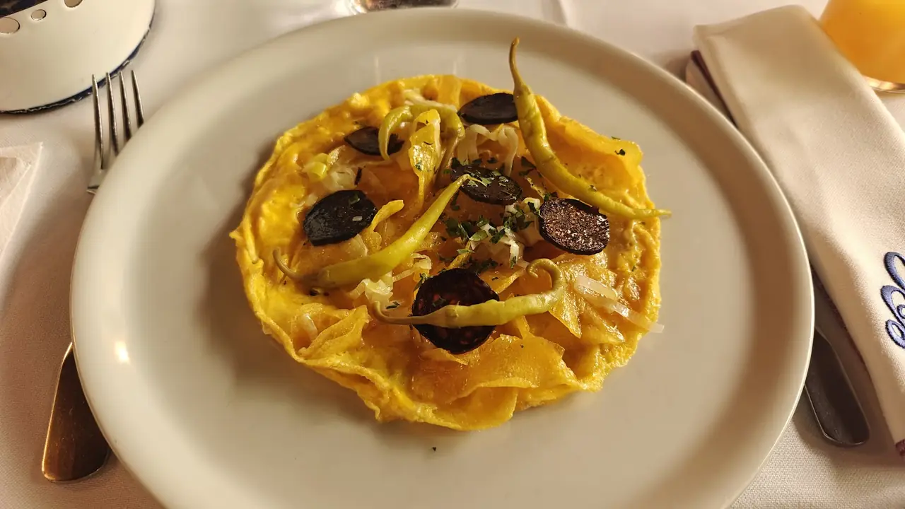 Open-faced omelette topped with dark truffle slices and green peppers on a white plate
