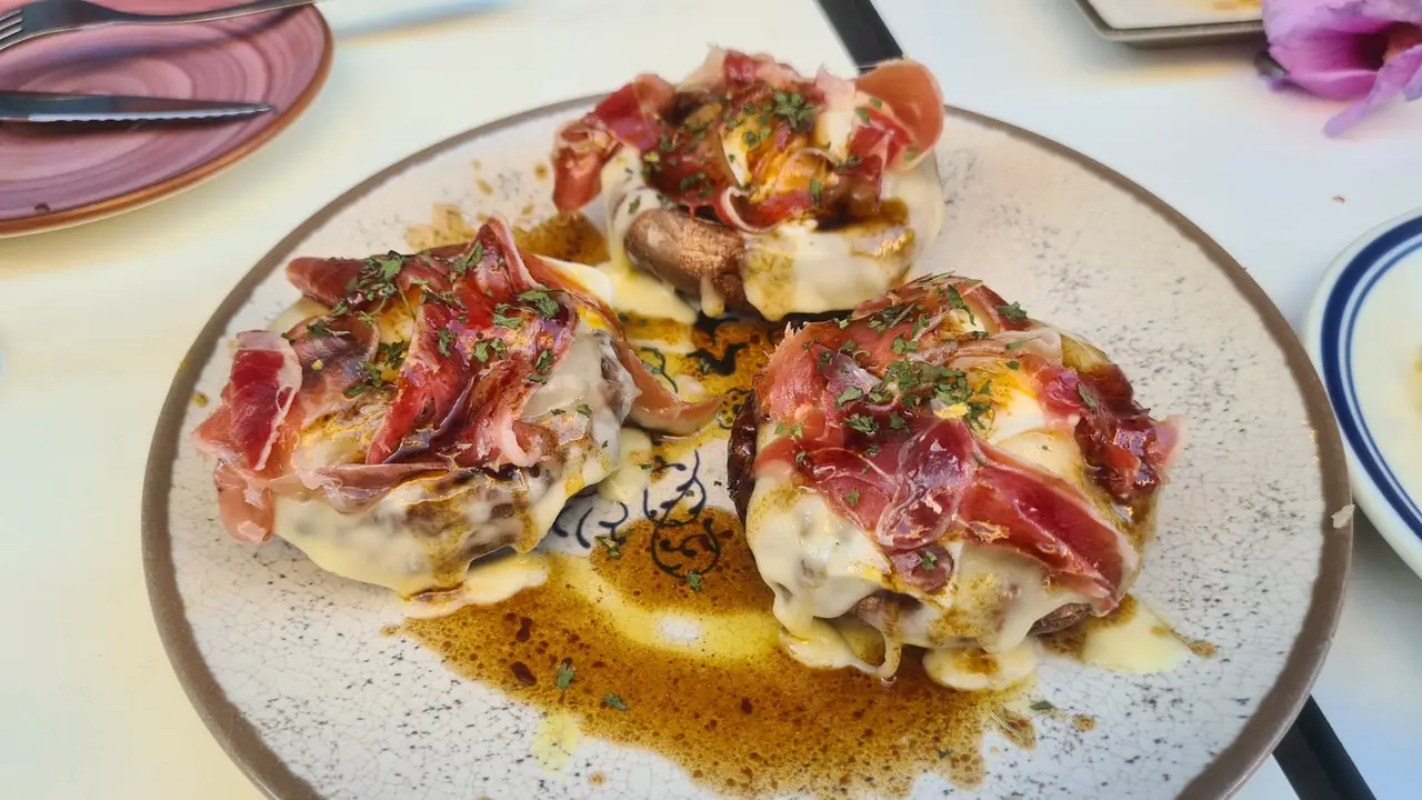 Stuffed mushroom caps topped with melted cheese, jamon and balsamic reduction