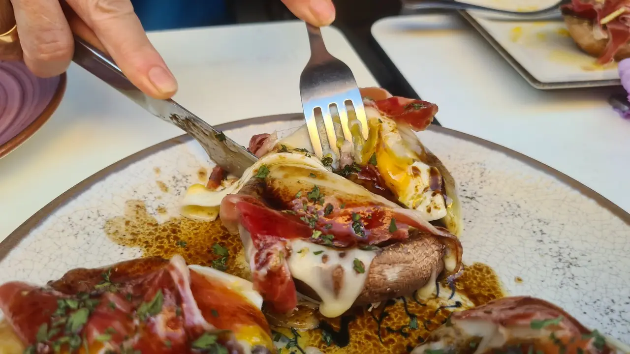 Diner cutting into a stuffed mushroom with jamon and melted cheese, close up