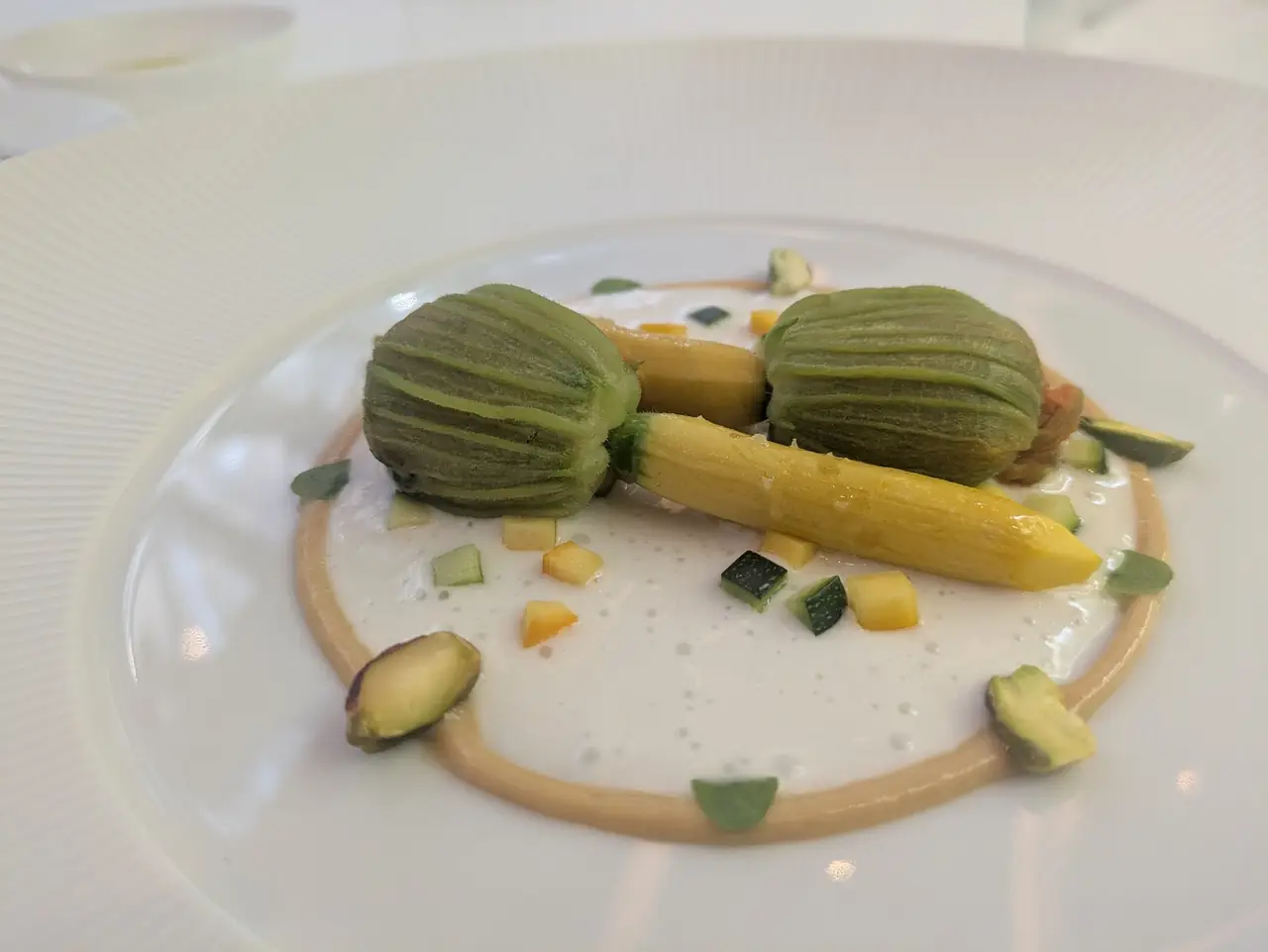 Plated stuffed courgette flowers with diced vegetables and cream sauce