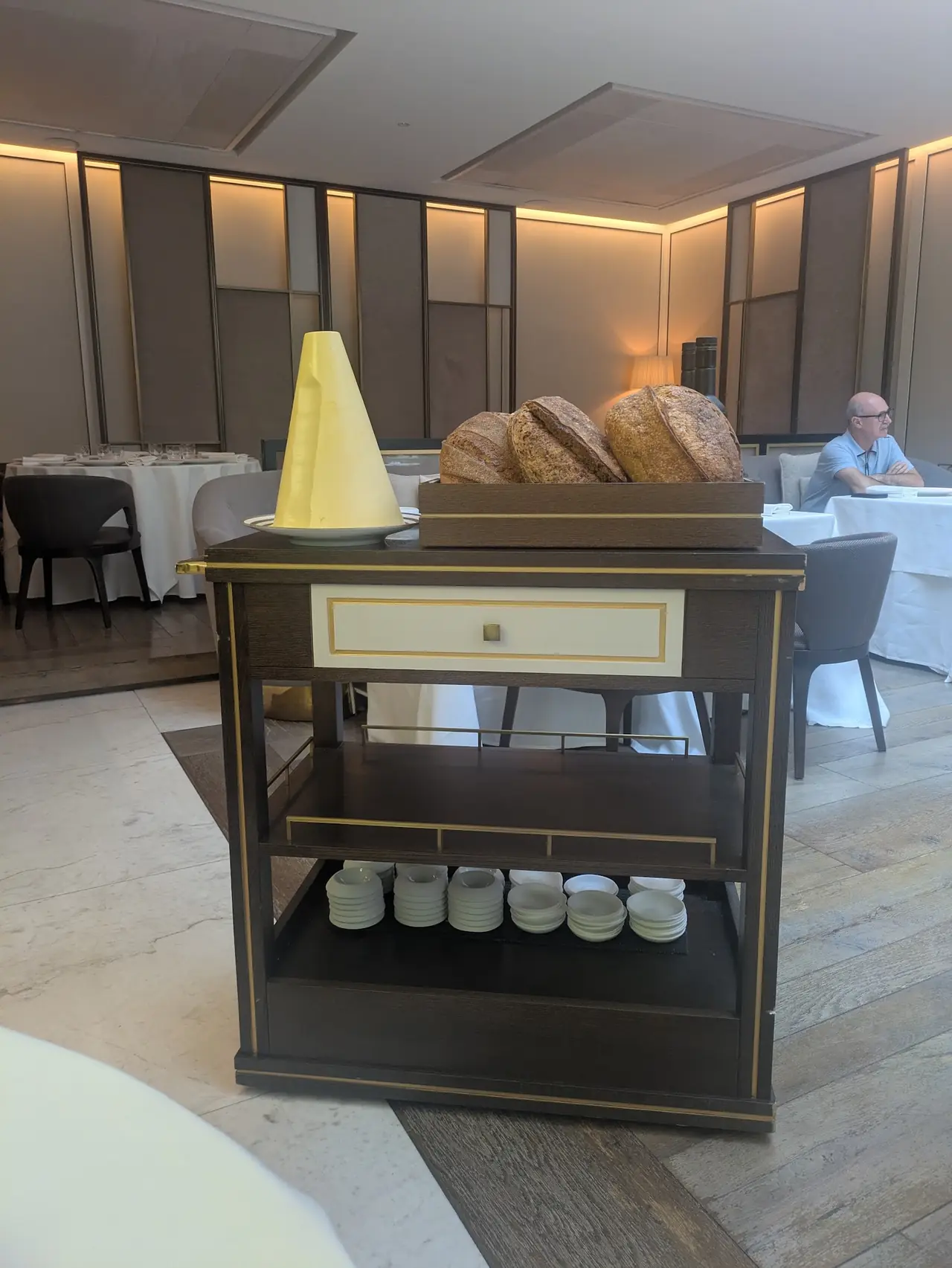Cart with fresh sourdough loaves and a conical butter, dining room in background