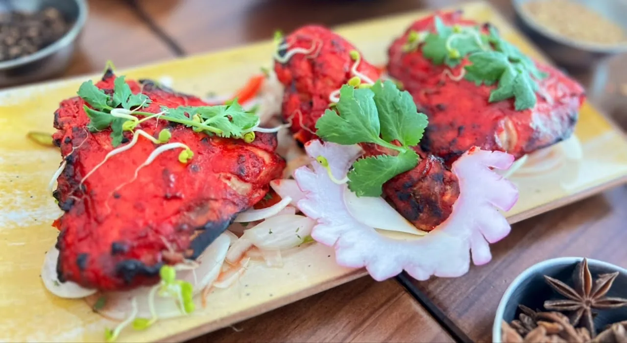 Tandoori chicken and paneer tikka skewers on a platter with mint chutney