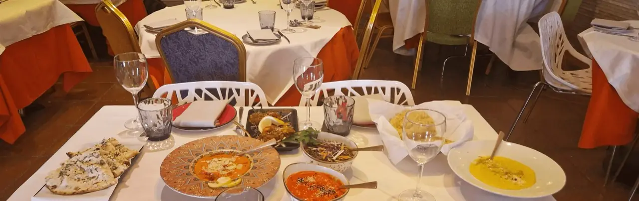 Indian restaurant table spread with naan bread, curries in decorative bowls, rice and grilled dishes, set in the dining room