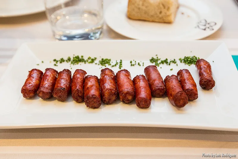A row of grilled chorizo sausages on a white plate