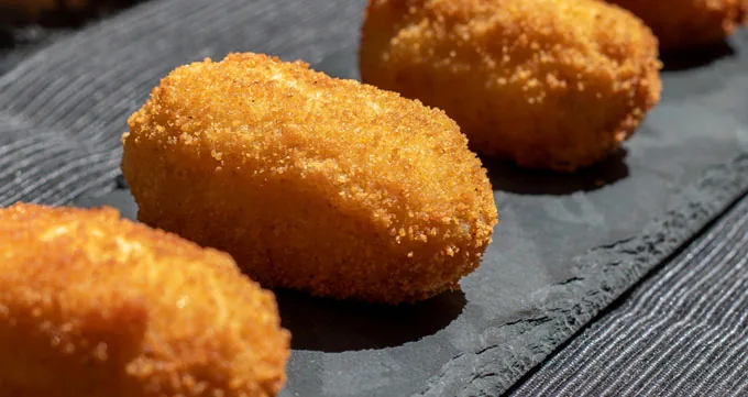 Three golden croquettes on a slate board