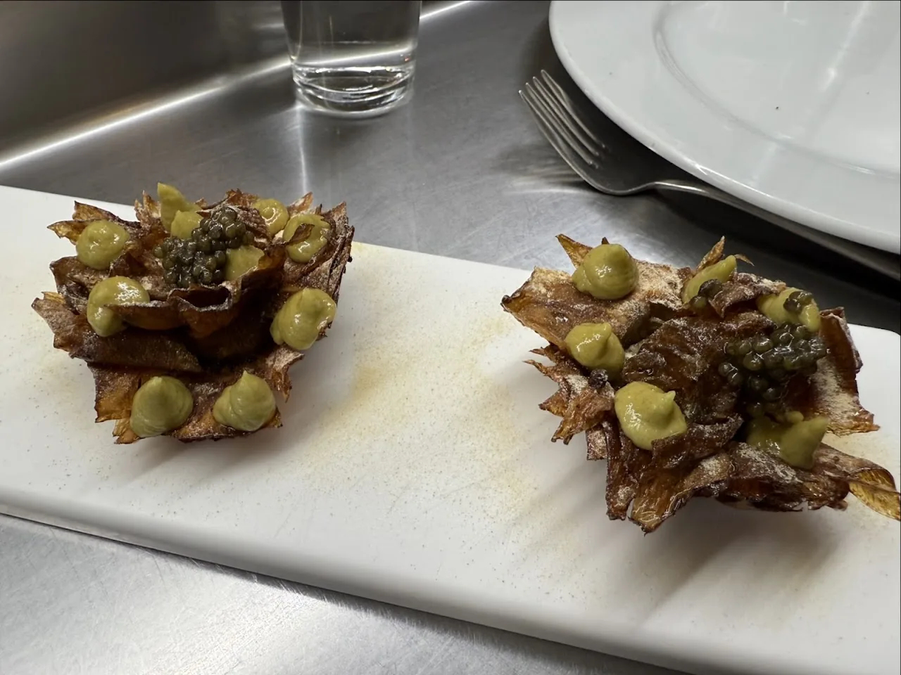 Two crispy fried artichoke appetizers on a metal board