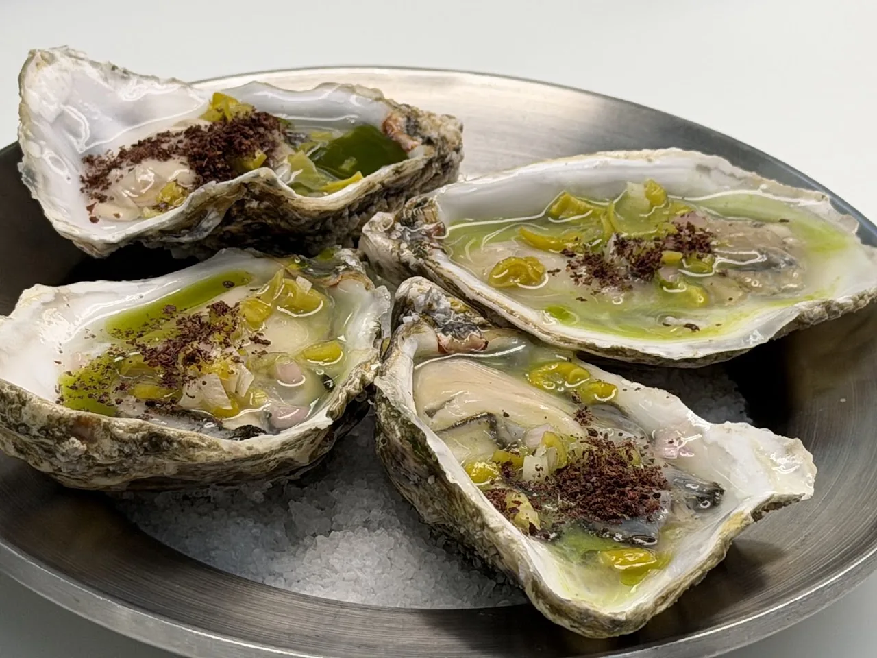 A plate of oysters on ice with a green herb dressing