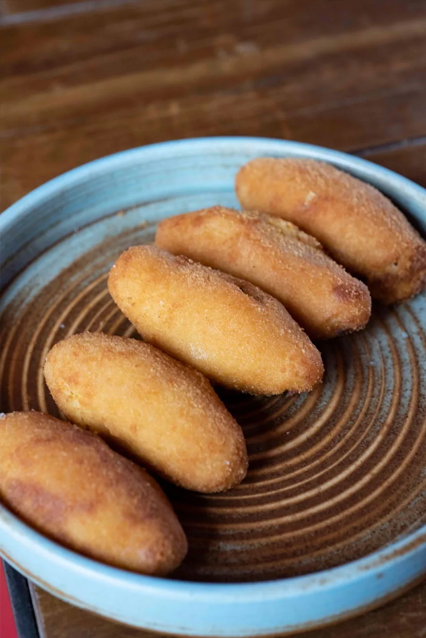 Five golden croquetas on a blue ceramic plate