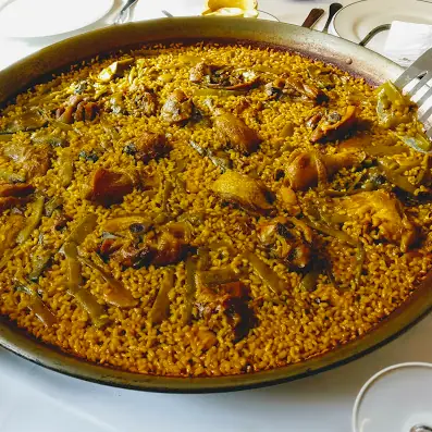 Overhead view of a paella pan filled with rice, chicken pieces, and green beans