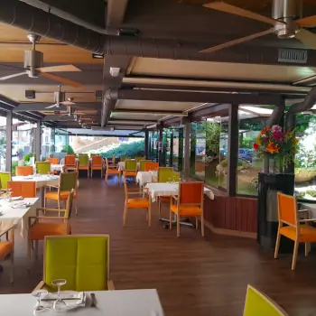 Restaurant terrace dining room with orange and green upholstered chairs set for service