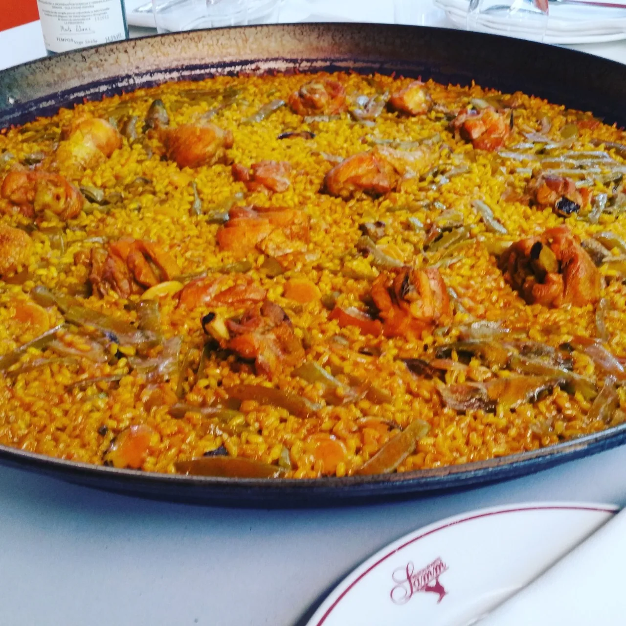 Close-up of a paella with chicken pieces and flat green beans