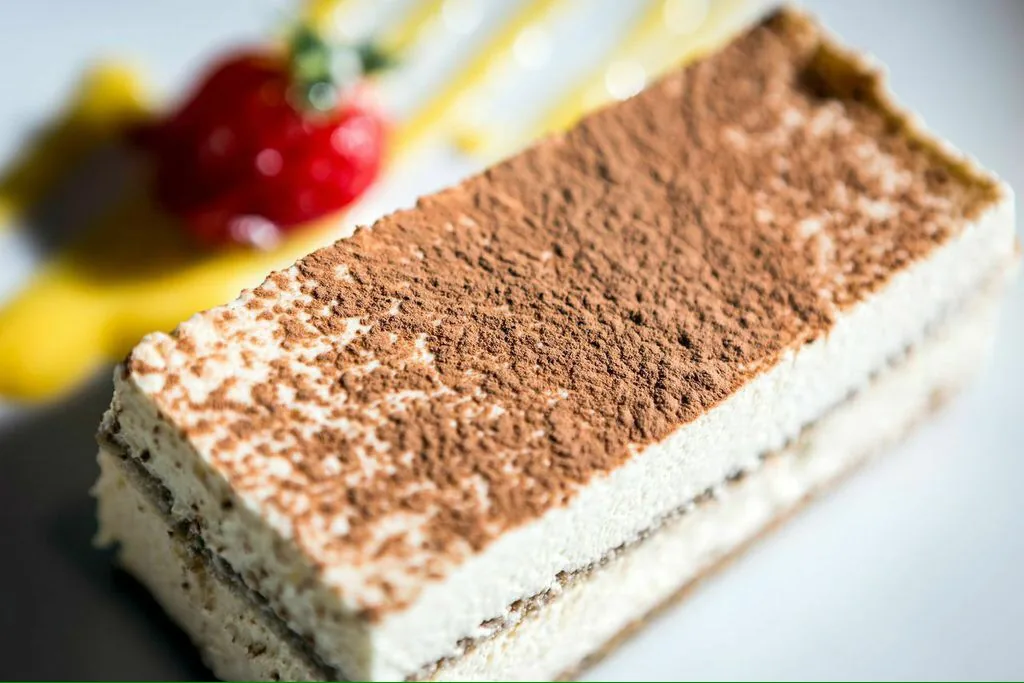 A tiramisu slice dusted with cocoa