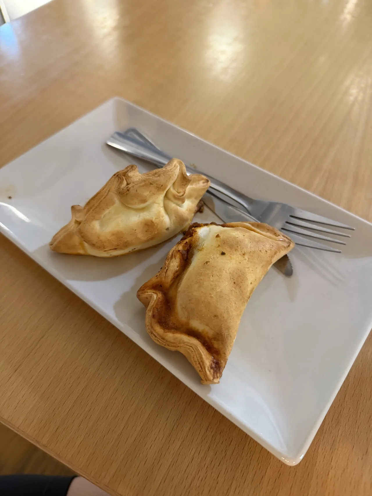 Two golden empanada pastries on a white plate