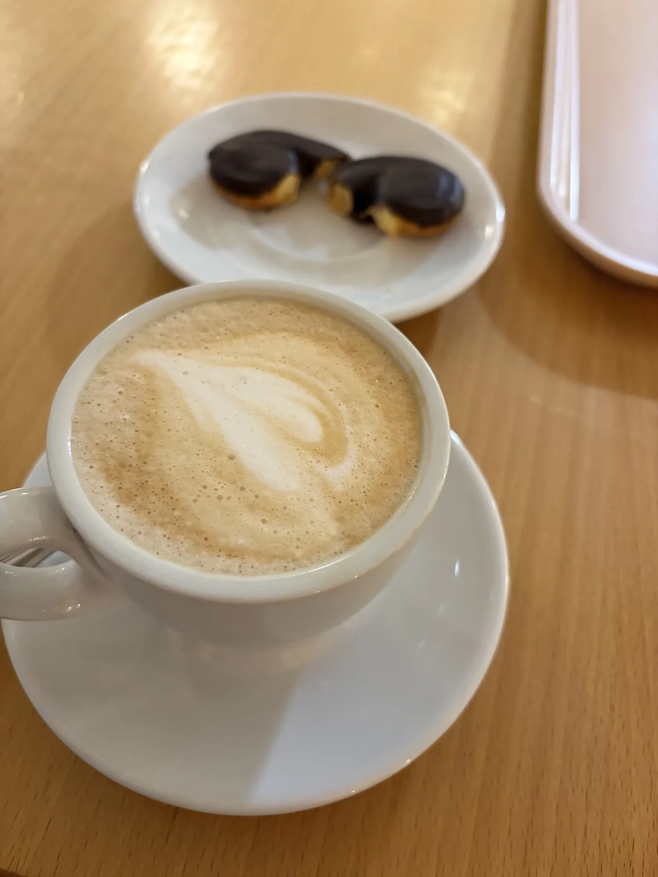 A cappuccino with two chocolate mini pastries on the side