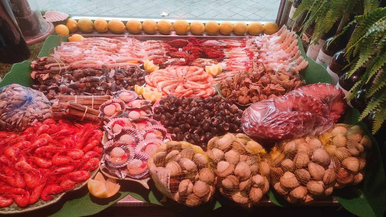 A seafood platter with assorted shellfish and cured meats on leaves